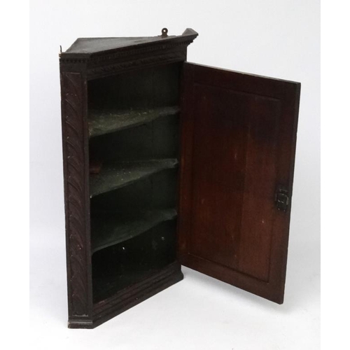 177 - A Georgian carved oak corner cupboard opening to reveal 3  green shaped shelves within. 38 3/4'' hig... 