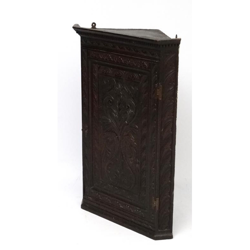 177 - A Georgian carved oak corner cupboard opening to reveal 3  green shaped shelves within. 38 3/4'' hig... 