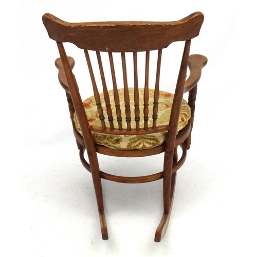 217 - An American oak and bentwood circular seated rocking chair with open arms. 34 1/2'' high