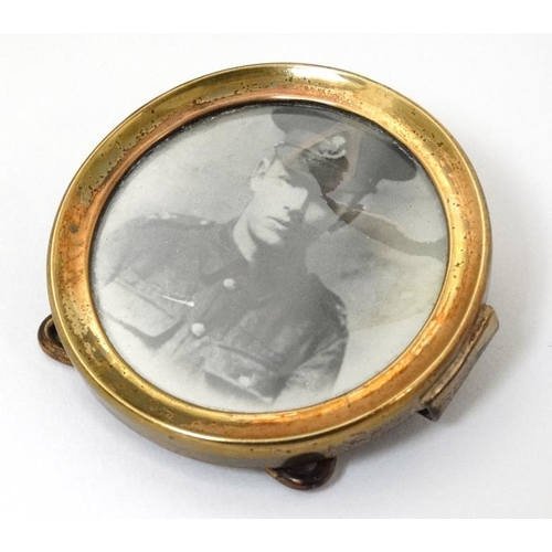 337 - Militaria : A small Trench Art brass circular Strut Frame , with uniform portrait photograph of a yo... 