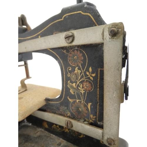 385 - Toy: A c1900 German Hand crank child's / miniature metal sewing machine, having floral decoration on... 