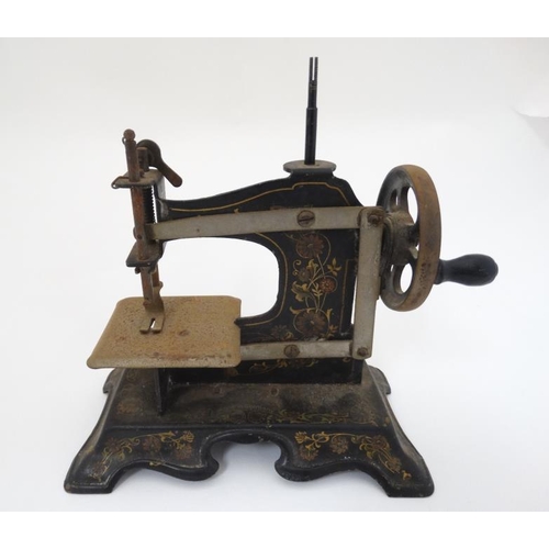 385 - Toy: A c1900 German Hand crank child's / miniature metal sewing machine, having floral decoration on... 