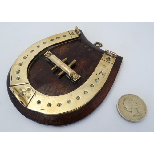 389 - A small brass cribbage board formed as a horseshoe, with two pegs and mounted upon a wooden plinth. ... 