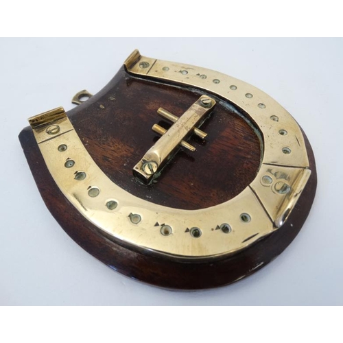 389 - A small brass cribbage board formed as a horseshoe, with two pegs and mounted upon a wooden plinth. ... 