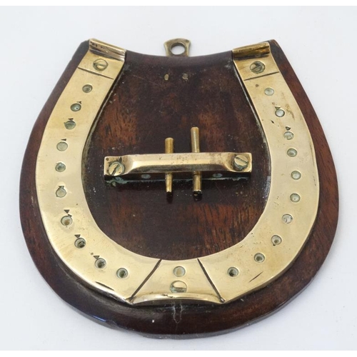 389 - A small brass cribbage board formed as a horseshoe, with two pegs and mounted upon a wooden plinth. ... 