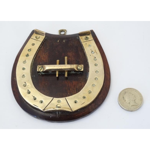 389 - A small brass cribbage board formed as a horseshoe, with two pegs and mounted upon a wooden plinth. ... 