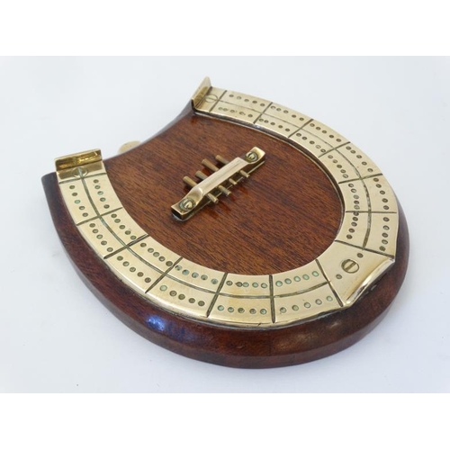 390 - A medium brass cribbage board formed as a horseshoe, with four pegs and mounted upon a wooden plinth... 