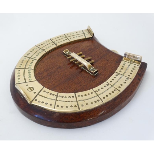 390 - A medium brass cribbage board formed as a horseshoe, with four pegs and mounted upon a wooden plinth... 