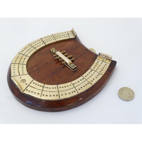 390 - A medium brass cribbage board formed as a horseshoe, with four pegs and mounted upon a wooden plinth... 