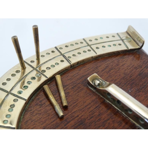 390 - A medium brass cribbage board formed as a horseshoe, with four pegs and mounted upon a wooden plinth... 