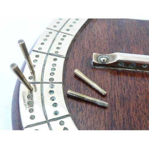 390 - A medium brass cribbage board formed as a horseshoe, with four pegs and mounted upon a wooden plinth... 