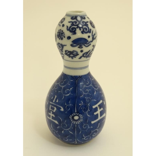 409 - A Chinese blue and white double gourd vase , decorated with scrolling foliage and Oriental symbols. ... 