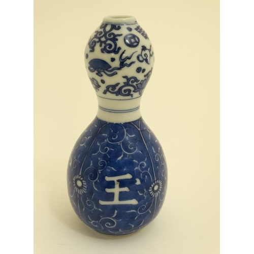 409 - A Chinese blue and white double gourd vase , decorated with scrolling foliage and Oriental symbols. ... 