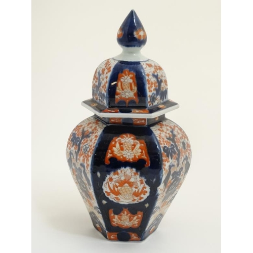 411 - A Japanese Imari pot and cover of hexagonal form , the sides hand painted with decorative floral pan... 