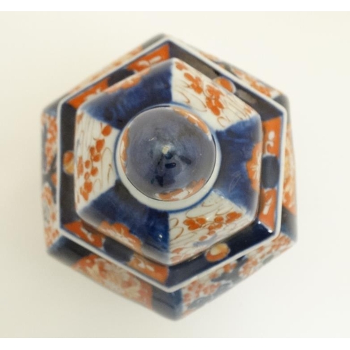 411 - A Japanese Imari pot and cover of hexagonal form , the sides hand painted with decorative floral pan... 