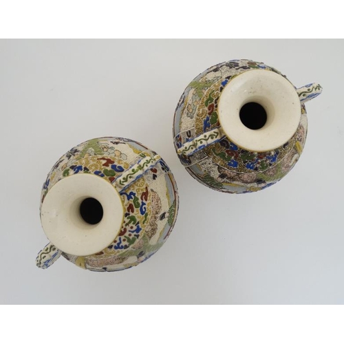 430 - A pair of Japanese Satsuma Moriage twin handled vases on tripod feet, each decorated in polychrome w... 