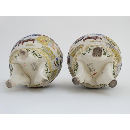 430 - A pair of Japanese Satsuma Moriage twin handled vases on tripod feet, each decorated in polychrome w... 