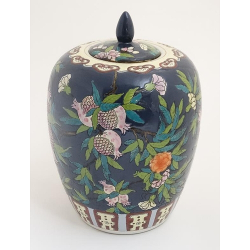 437 - A Chinese ginger jar and cover decorated with pink pomegranates and leaves on a navy ground, bears r... 