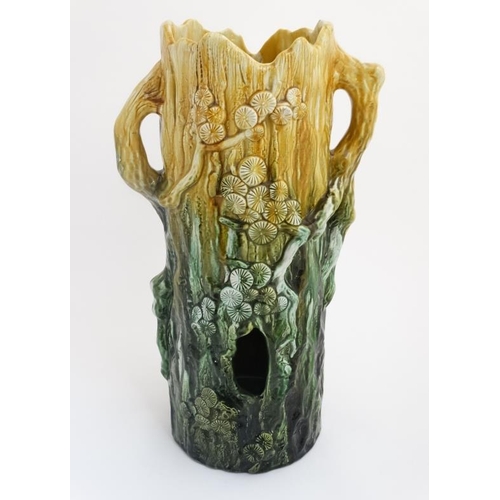 442 - A c1900 Majolica stick stand formed as a tree stump with trailing flora in shades of yellow and gree... 