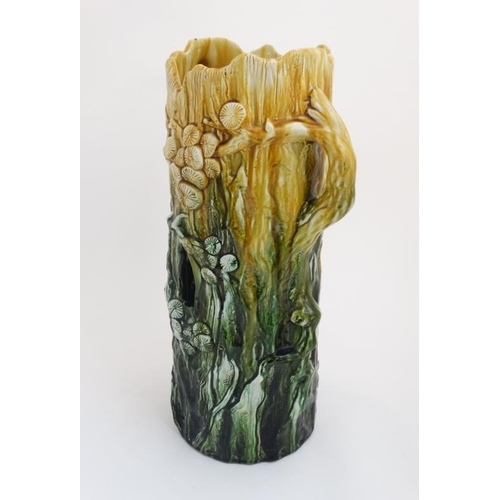 442 - A c1900 Majolica stick stand formed as a tree stump with trailing flora in shades of yellow and gree... 