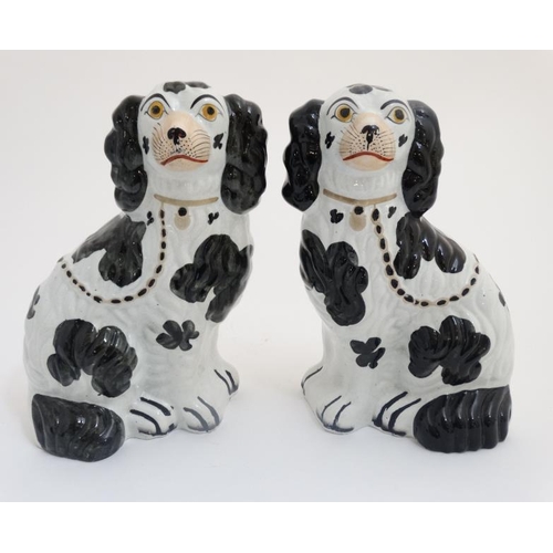 454 - A pair of 19thC black and white Staffordshire Spaniels,  having gilt coloured chair and collar, each... 