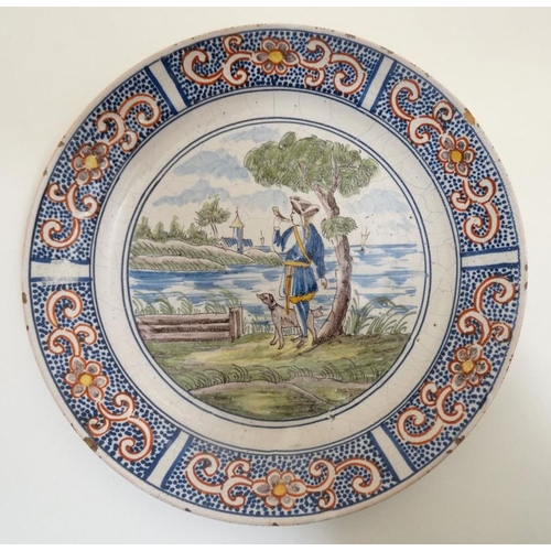 455 - An early 19thC Dutch Delft plate , decorated with figure and dog beside the sea with building in the... 