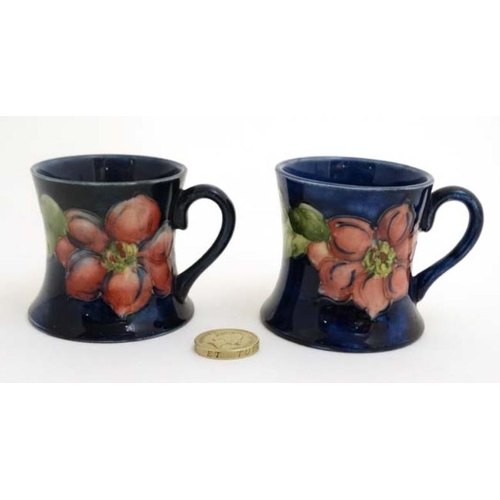 472 - A pair of Moorcroft Miniature ' Clematis ' pattern tankards on a cobalt blue ground , one bears orig... 