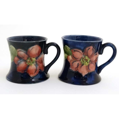 472 - A pair of Moorcroft Miniature ' Clematis ' pattern tankards on a cobalt blue ground , one bears orig... 