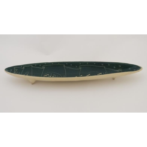 480 - An elongated ceramic dish decorated with musical notes in cream on a green ground. 16'' long.