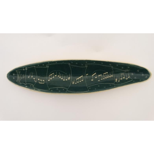 480 - An elongated ceramic dish decorated with musical notes in cream on a green ground. 16'' long.