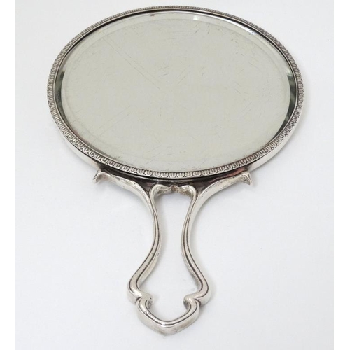 517 - An Art Nouveau silver hand mirror with floral and scroll decoration. Hallmarked London 1905 maker Ch... 