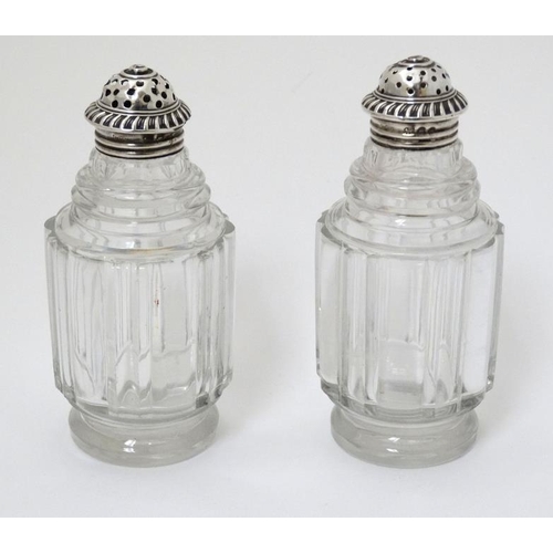 519 - A pair of glass pepperettes with 19thC silver tops. 4 1/2'' high