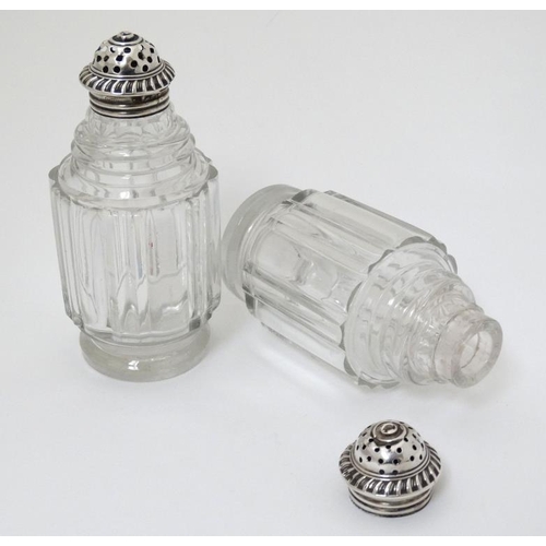 519 - A pair of glass pepperettes with 19thC silver tops. 4 1/2'' high