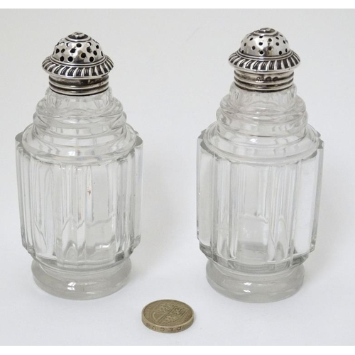 519 - A pair of glass pepperettes with 19thC silver tops. 4 1/2'' high