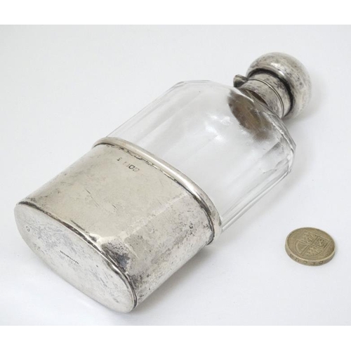 524 - A cut glass hip flask with silver beaker to lower section an silver mounts and top, hallmarked Londo... 