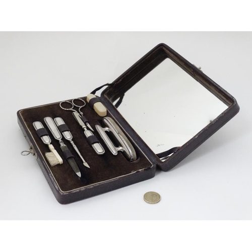 539 - A leather vanity/ manicure case with hinged lid having mirror under and containing 7 various items m... 