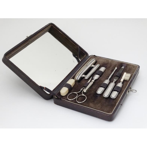 539 - A leather vanity/ manicure case with hinged lid having mirror under and containing 7 various items m... 