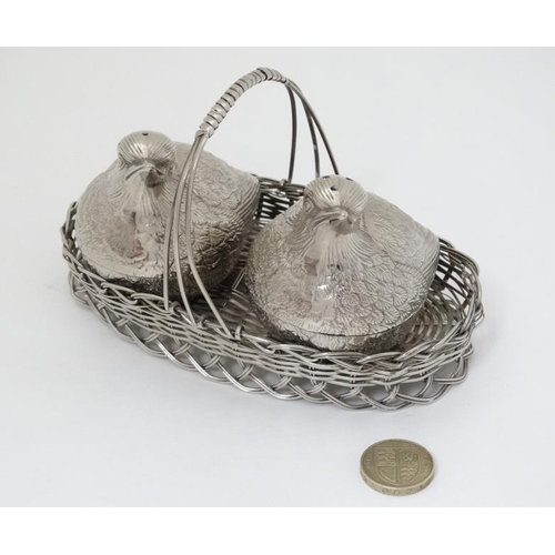 580 - A novelty cruet set comprising a pair of salt and pepper pots formed as chicks in a basket. 6'' wide