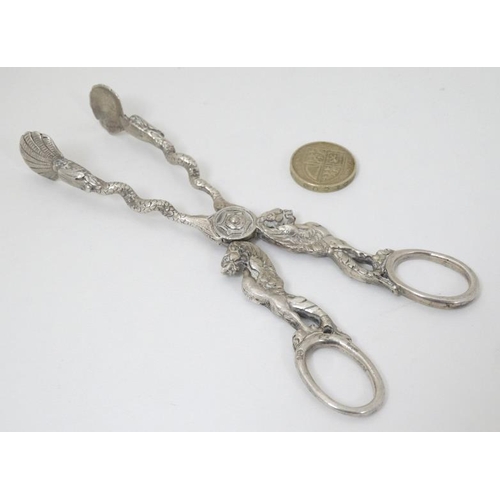 601 - A pair of silver plate sugar nips with wyvern and snake decoration with scallop shell formed grips. ... 