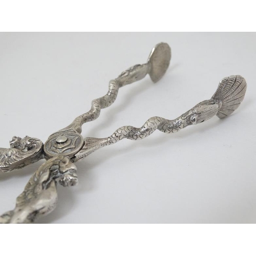 601 - A pair of silver plate sugar nips with wyvern and snake decoration with scallop shell formed grips. ... 