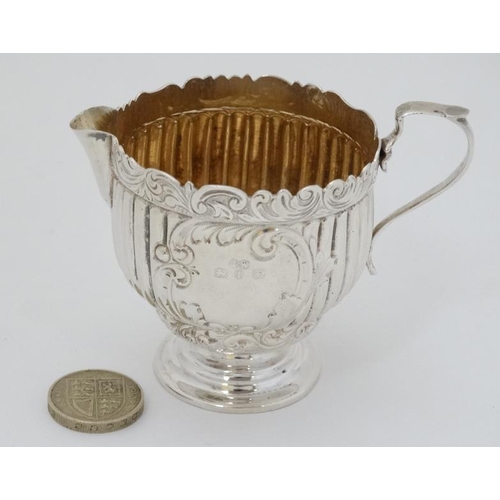 614 - A silver cream jug with fluted and embossed decoration and gilded interior. Hallmarked Birmingham 18... 