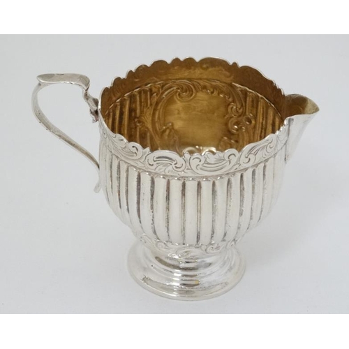 614 - A silver cream jug with fluted and embossed decoration and gilded interior. Hallmarked Birmingham 18... 