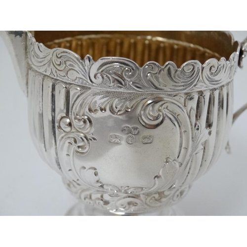 614 - A silver cream jug with fluted and embossed decoration and gilded interior. Hallmarked Birmingham 18... 