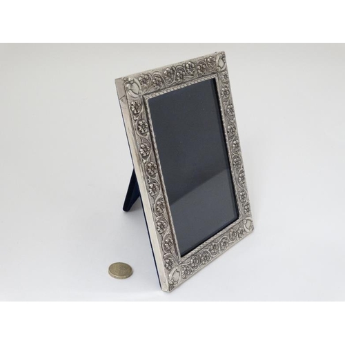 636 - A white metal photograph frame with floral and scroll decoration, marked '925'  with easel / strut b... 