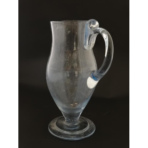 646 - A tall clear glass pedestal jug with loop handle 11'' high