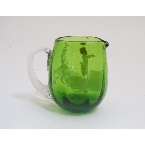 654 - A green glass jug with clear glass loop handle and Mary Gregory style decoration. 3 1/2'' high