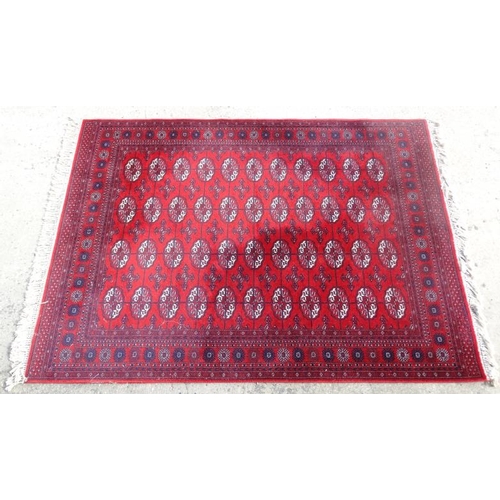 77 - Rug / Carpet :   A woollen Bokara Rug with wine red ground and 4 x 11 (44) botehs to center ,  99 x ... 