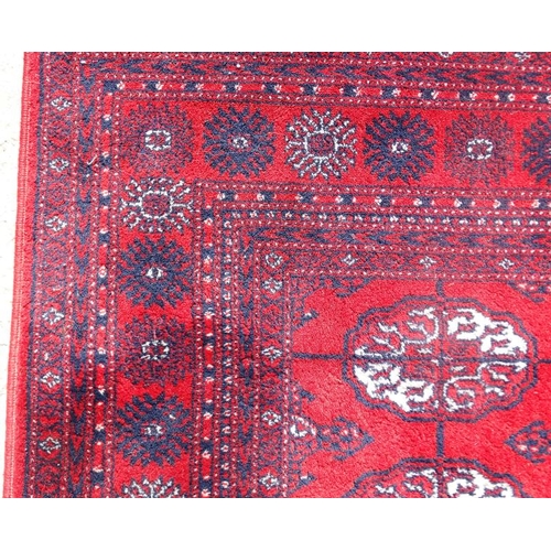 77 - Rug / Carpet :   A woollen Bokara Rug with wine red ground and 4 x 11 (44) botehs to center ,  99 x ... 