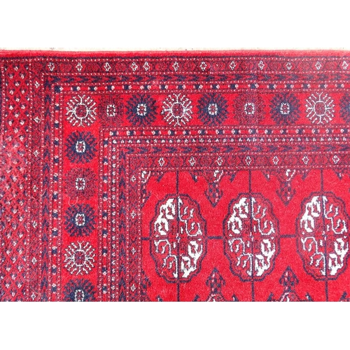 77 - Rug / Carpet :   A woollen Bokara Rug with wine red ground and 4 x 11 (44) botehs to center ,  99 x ... 