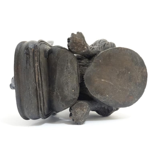 813 - A 21st carved black forest inkwell formed as a dachshund dog with hinged head and holding a satchel ... 